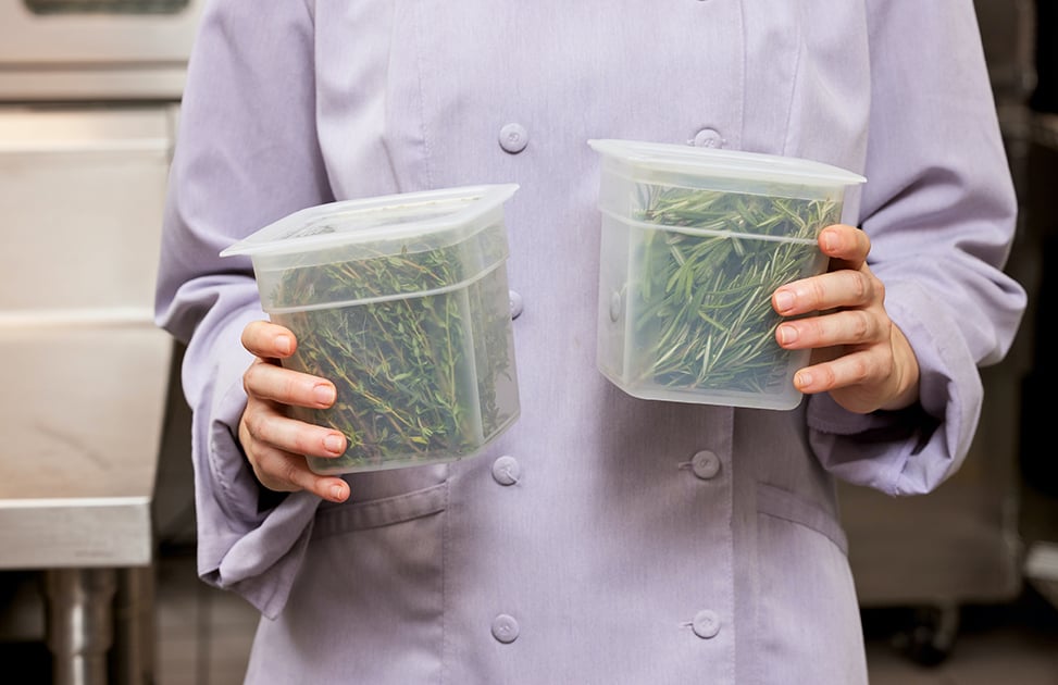 Closeup of a chef holding two small Cambro Camsquare containers.