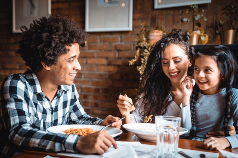 Mother sitting with daughter and husband in restaurant enjoying dinner