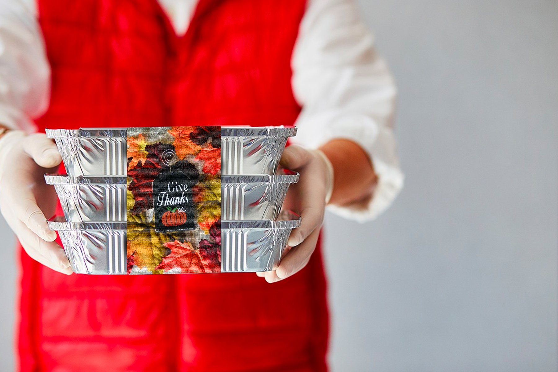 Restaurant worker holding Thanksgiving to go plates with wrapping that reads - Give Thanks