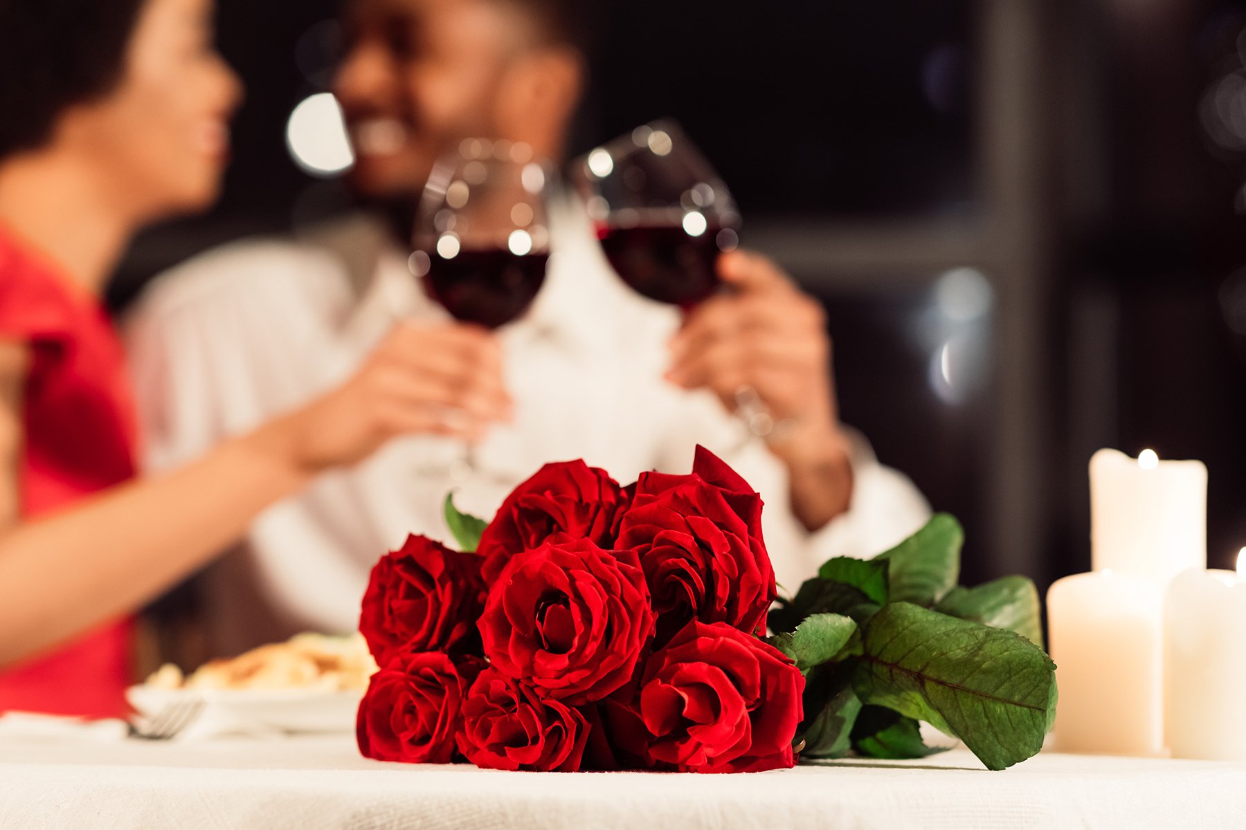 Roses on a table with blurred couple in the background having dinner at a restaurant