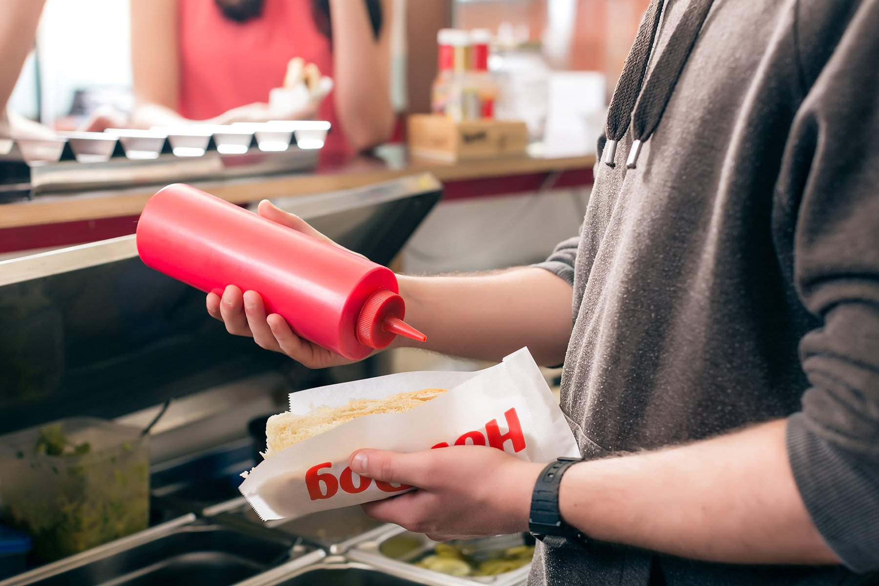 Hot dog vendor putting ketchup on a hot dog