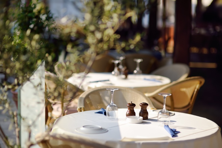 Springtime outdoor seating with sunlight and plants surrounding set table