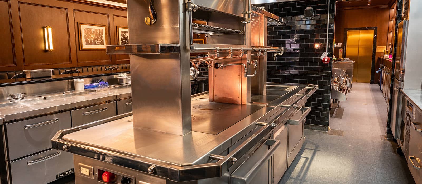 Great Jones Distilling kitchen with stainless steal and wood grain walls