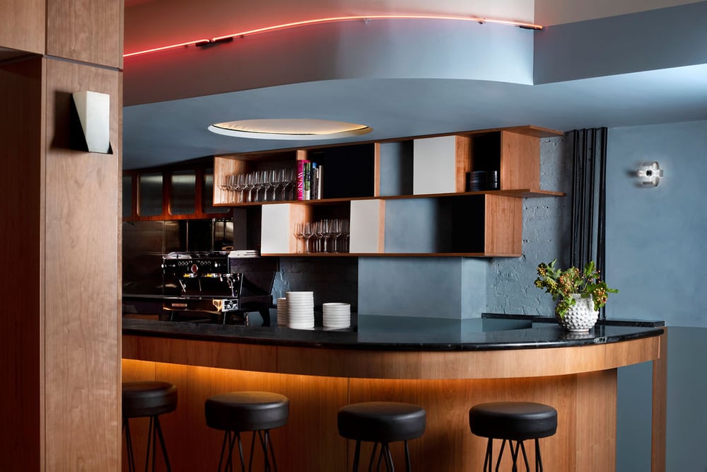 Shot of the obsidian-topped bar with wine glasses in cabinets behind it