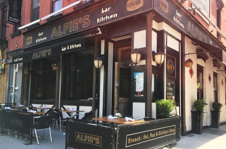 Corner shot of the outside of Alfie's Bar and Kitchen showcasing their outdoor tables in front of the restaurant
