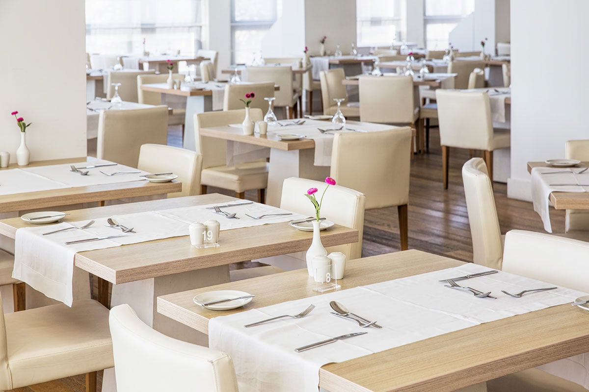 Beautiful restaurant interior with tables set and light color scheme