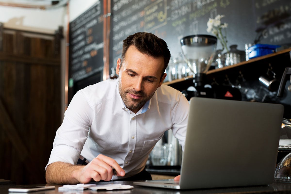 Man in front of laptop checking mobile phone