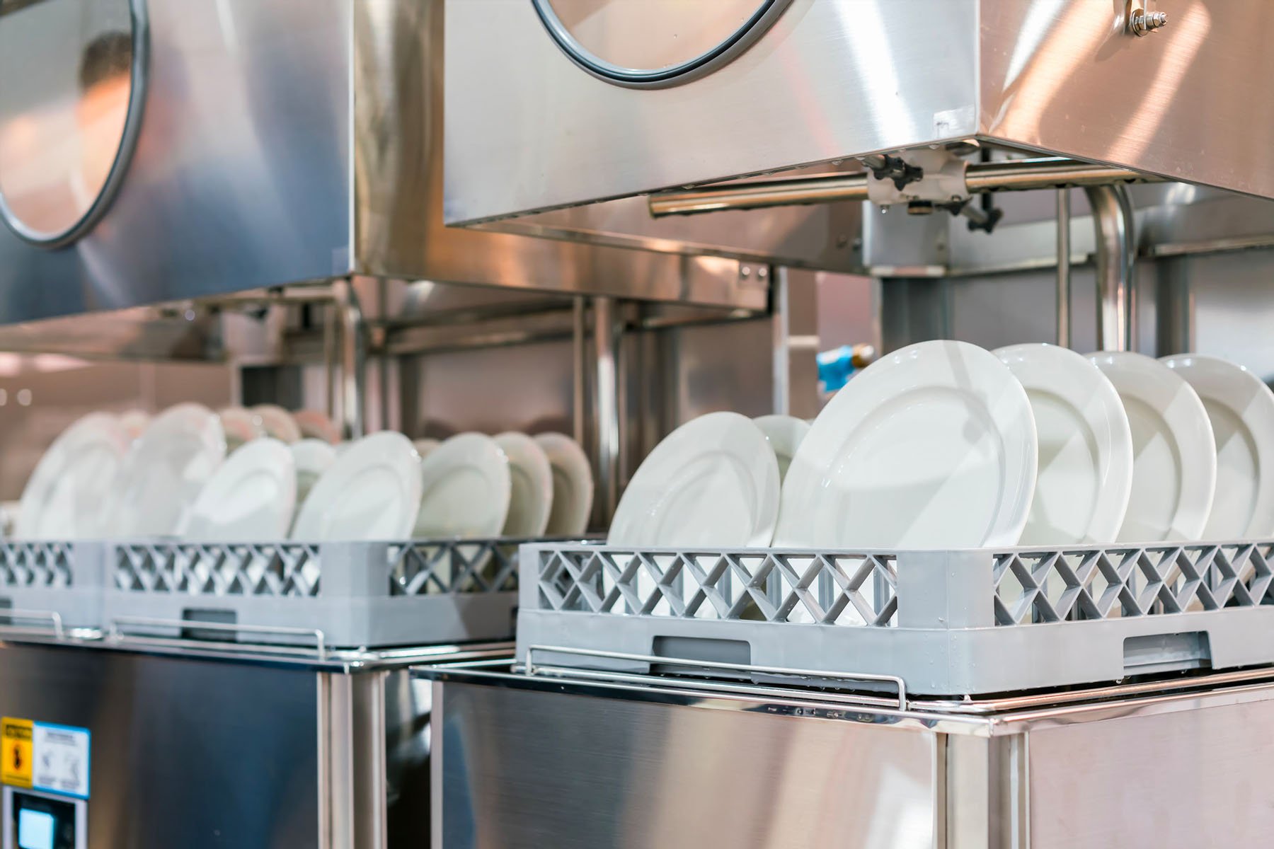 close up white plate on basket in automatic dishwasher machine for industrial