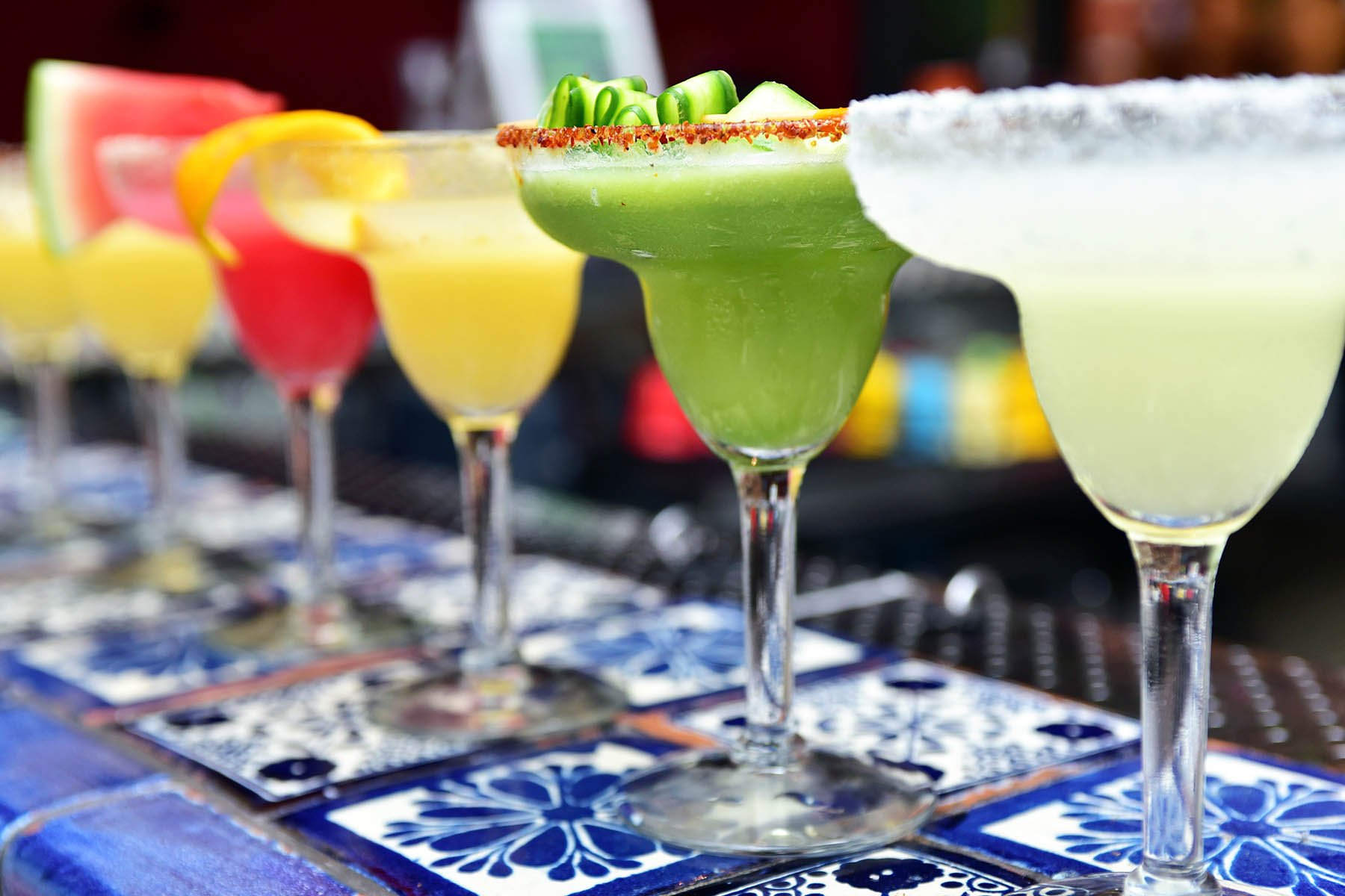 A row of frozen margaritas in cocktail glasses on a bar