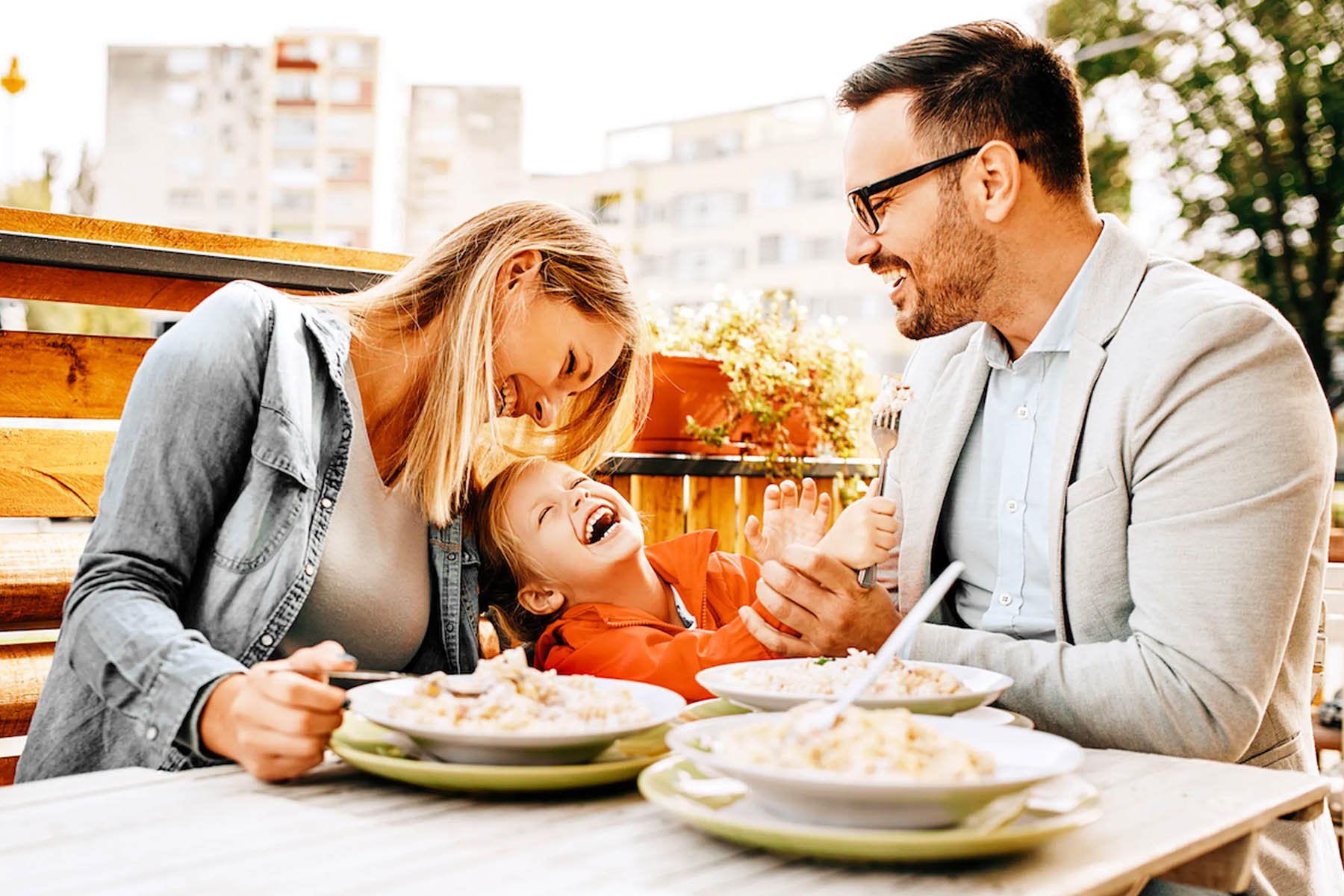 Laughing mother father and child enjoying breakfast together at a restaurant