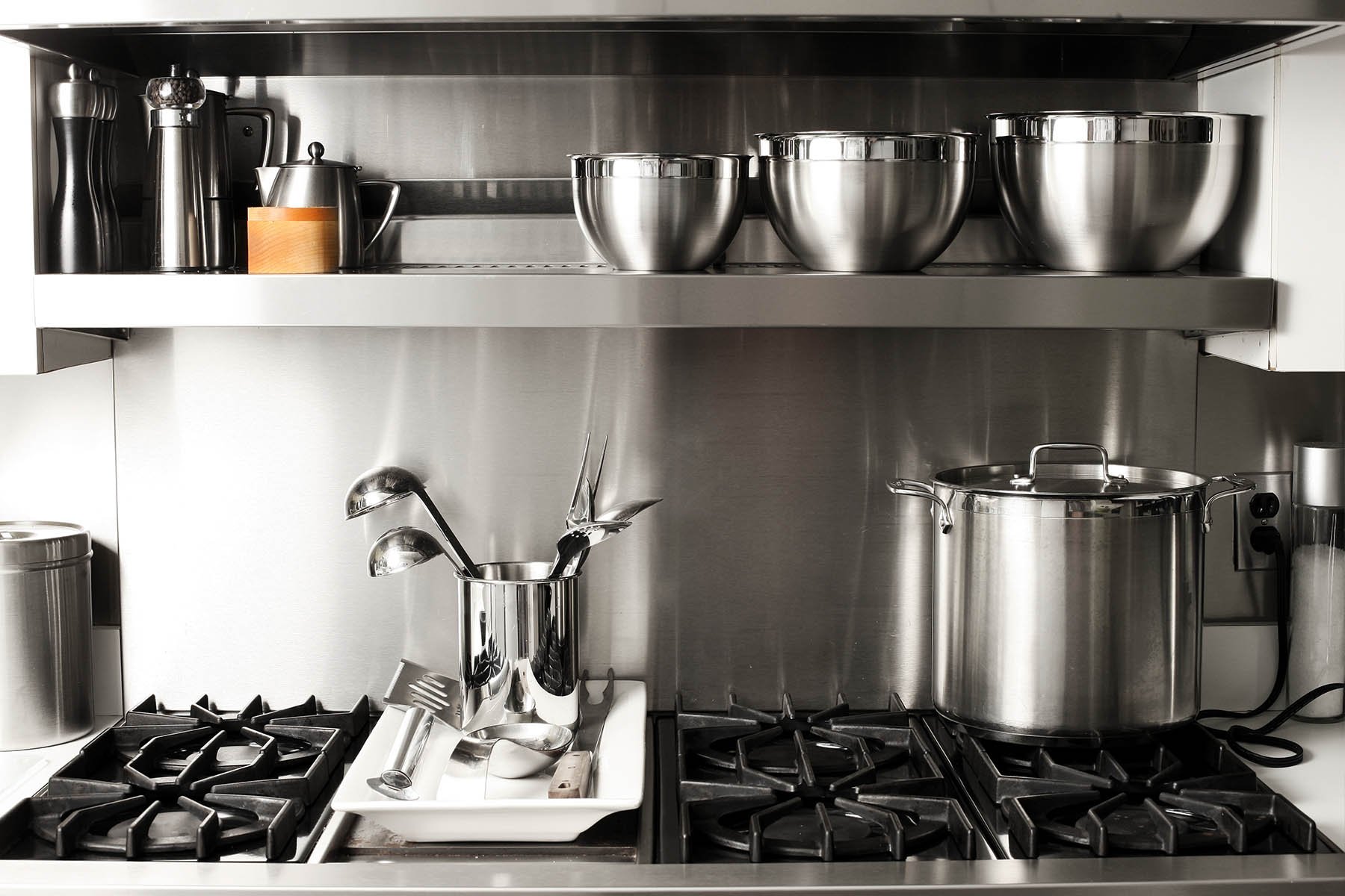 restaurant kitchen stove with smallwares like ladles and spatulas displayed on the stove