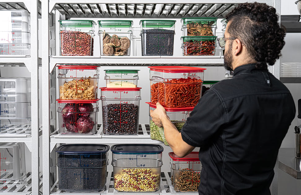 A person placing Cambro Camsquares on a shelf.