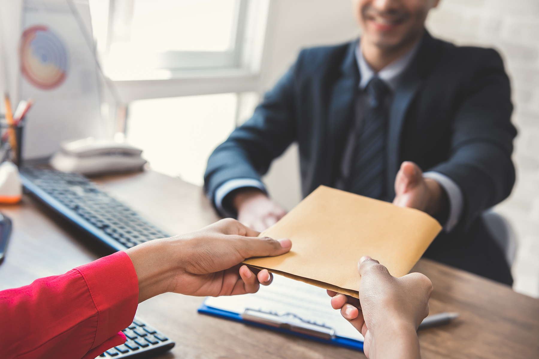 Restaurant owner handing envelope of forms and money to businessman