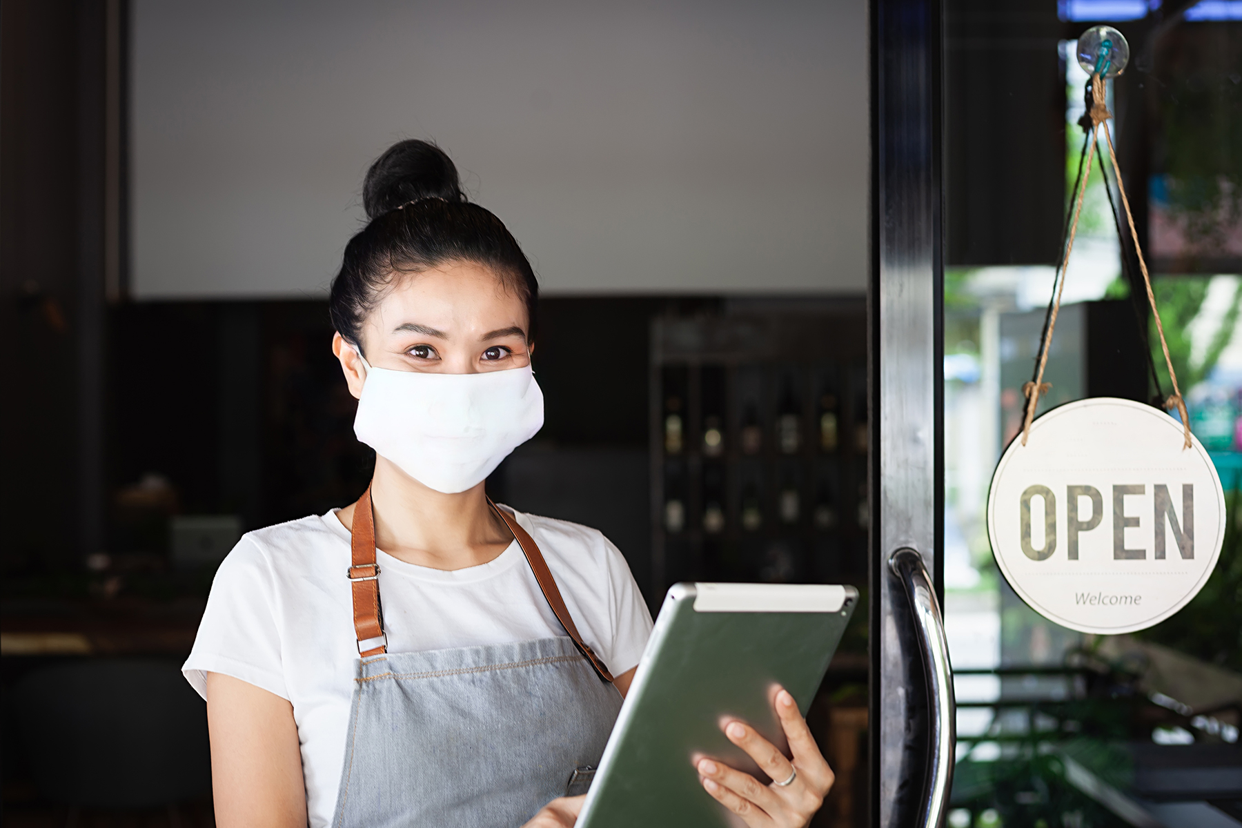 Restaurant worker with clipboard standing next to restaurant an OPEN sign