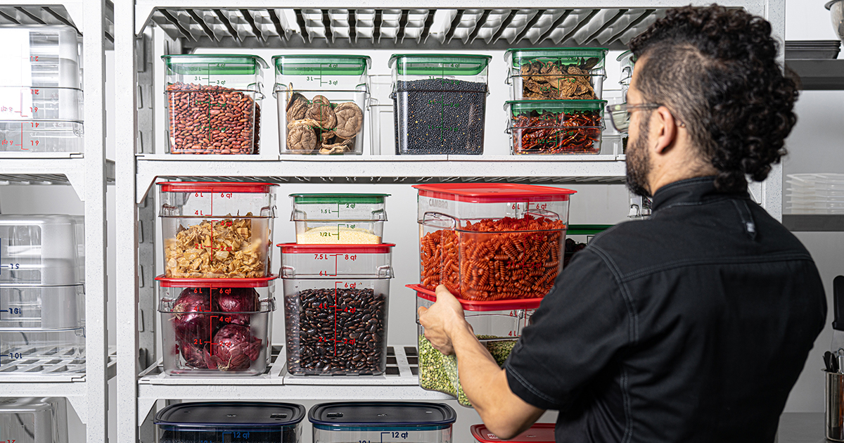 A person placing Cambro Camsquares on a shelf.