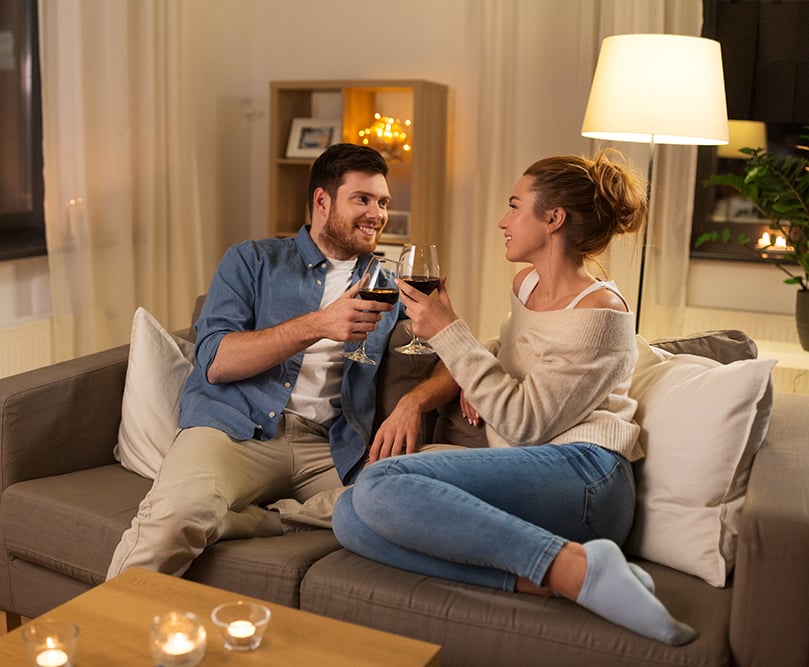 Couple sitting on couch drinking wine in warm, winter home