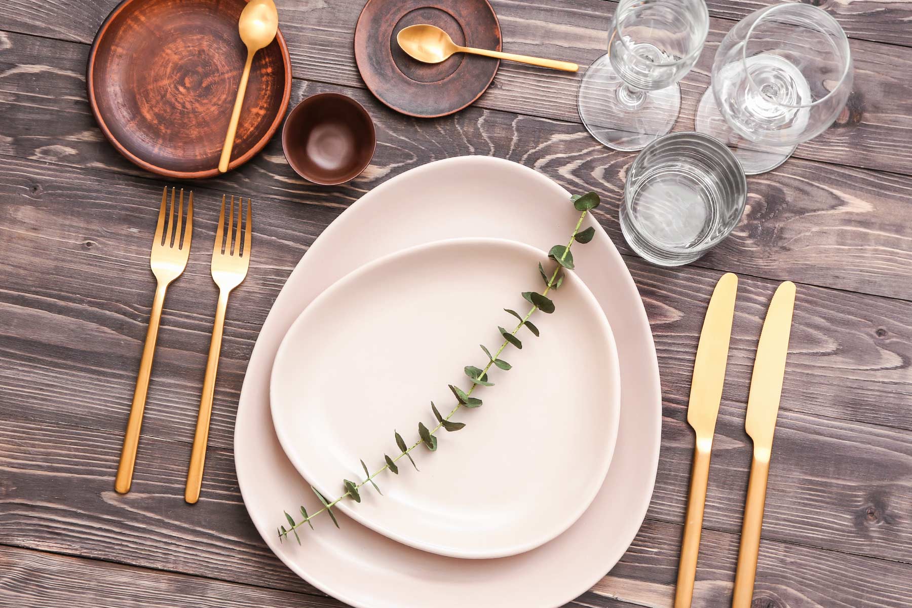 Overhead view of modern dining setup, with forks, knives, wine glasses