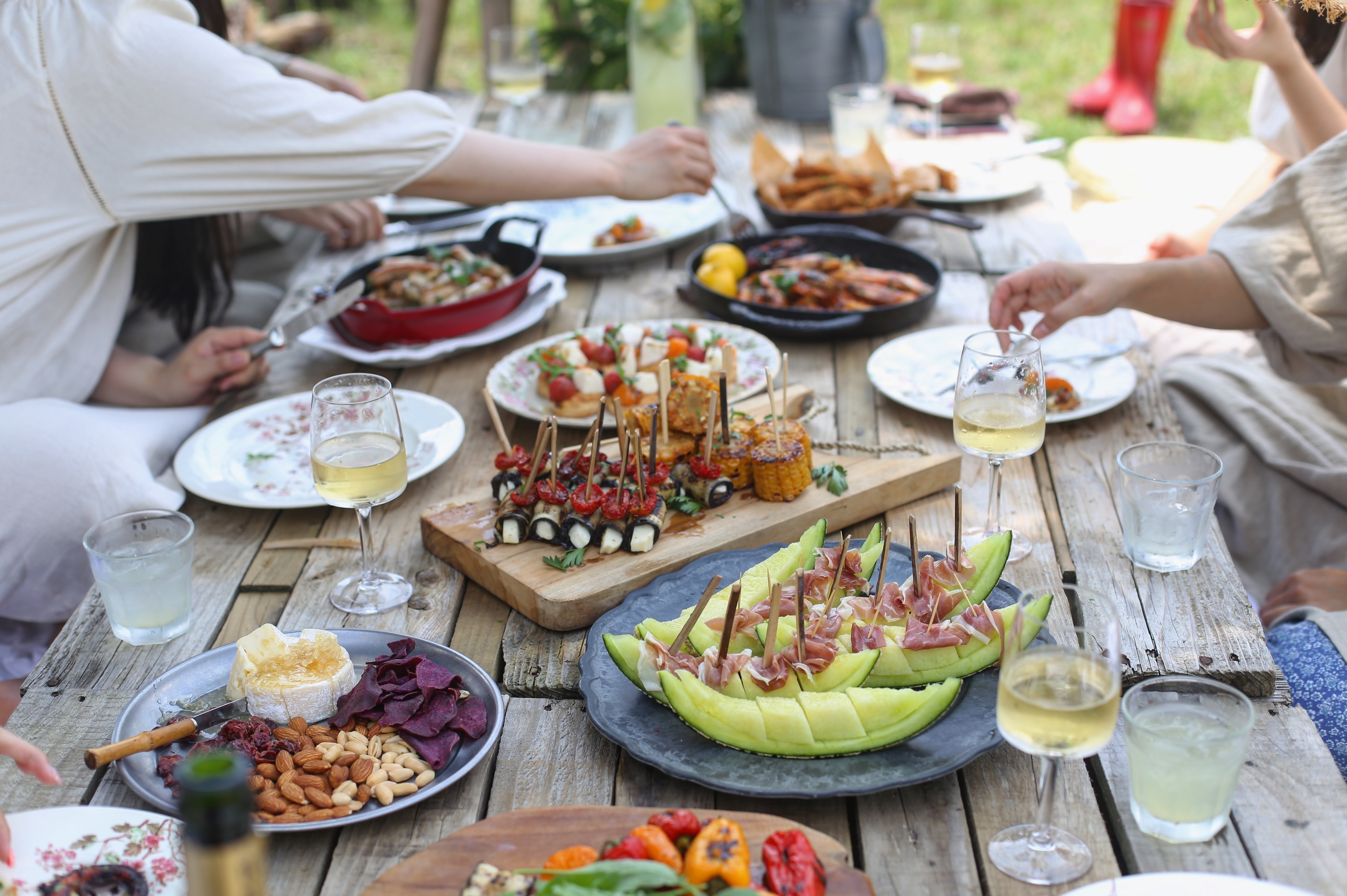 assorted appetizers on picnic table with guests grabbing food